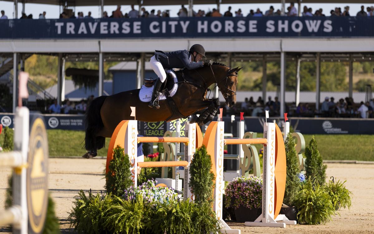 A horse and rider jump in front of the Traverse City Horse Shows grandstand