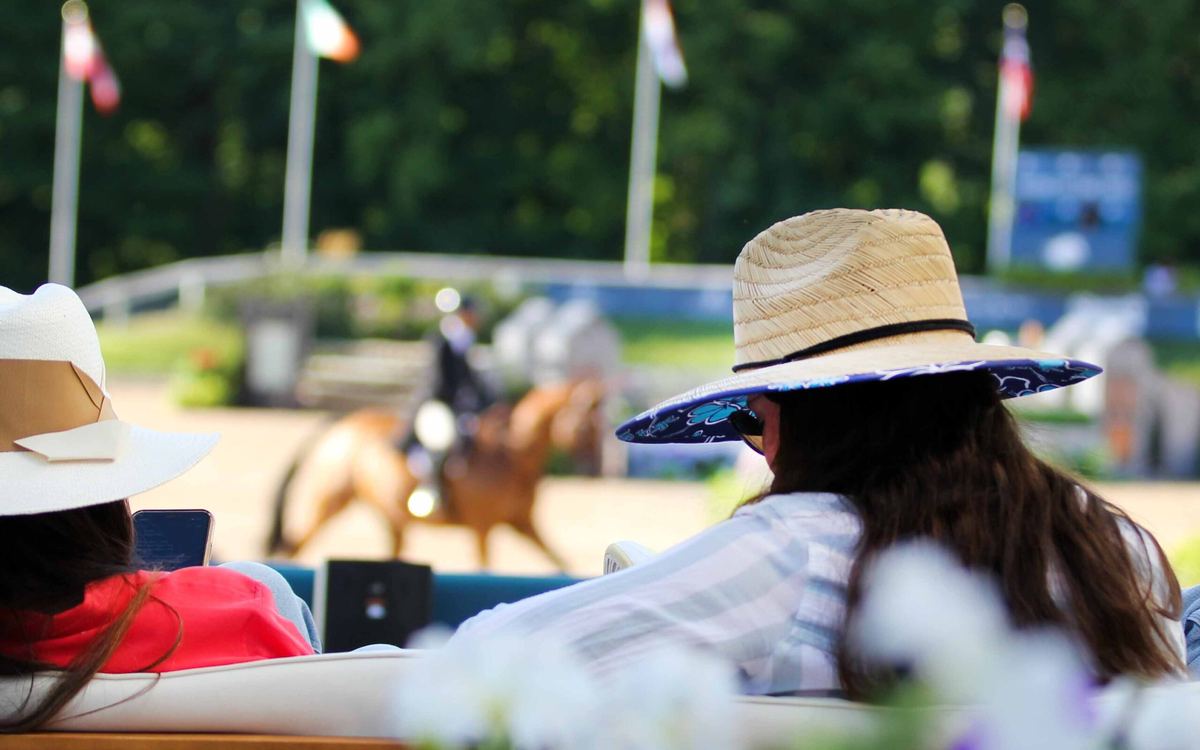 Spectators in sun hats watch from ringside at Flintfields Horse Park